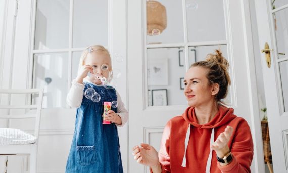 A joyful moment of a mother and daughter playing with bubbles indoors.
